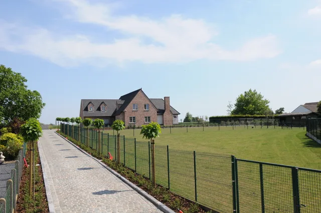 Vrijstaande woning met rode gevelsteen op ruim perceel met inrijlaan en aangeplante tuin