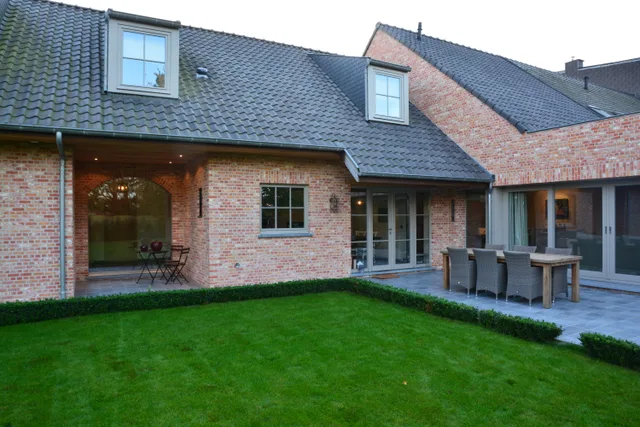 Moderne bakstenen woning met schildaken, tuinzijde met terras en grasperk