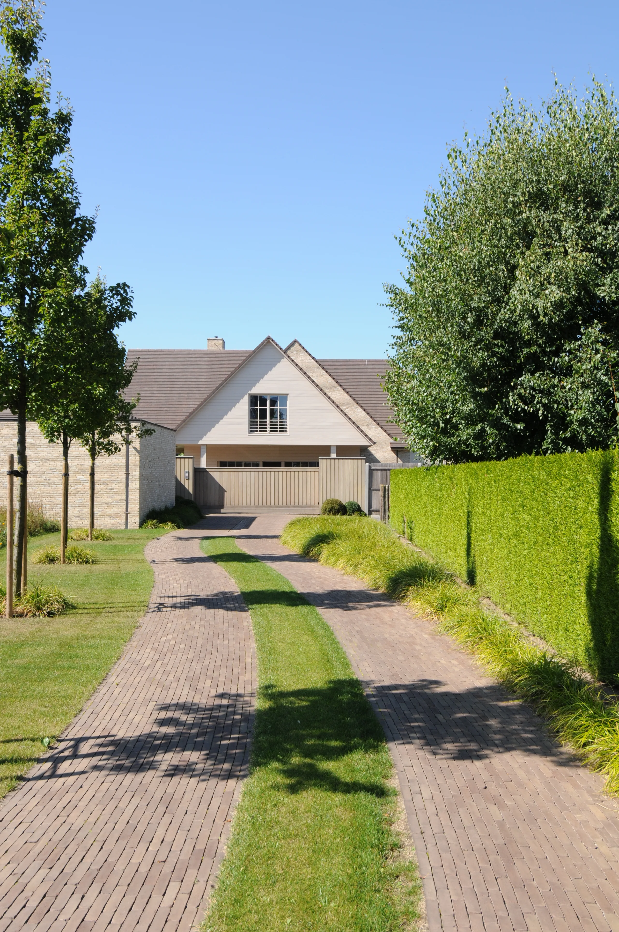 Nieuwbouwwoning met witte crepi gevel en inrit afgewerkt met tegels en grasstroken