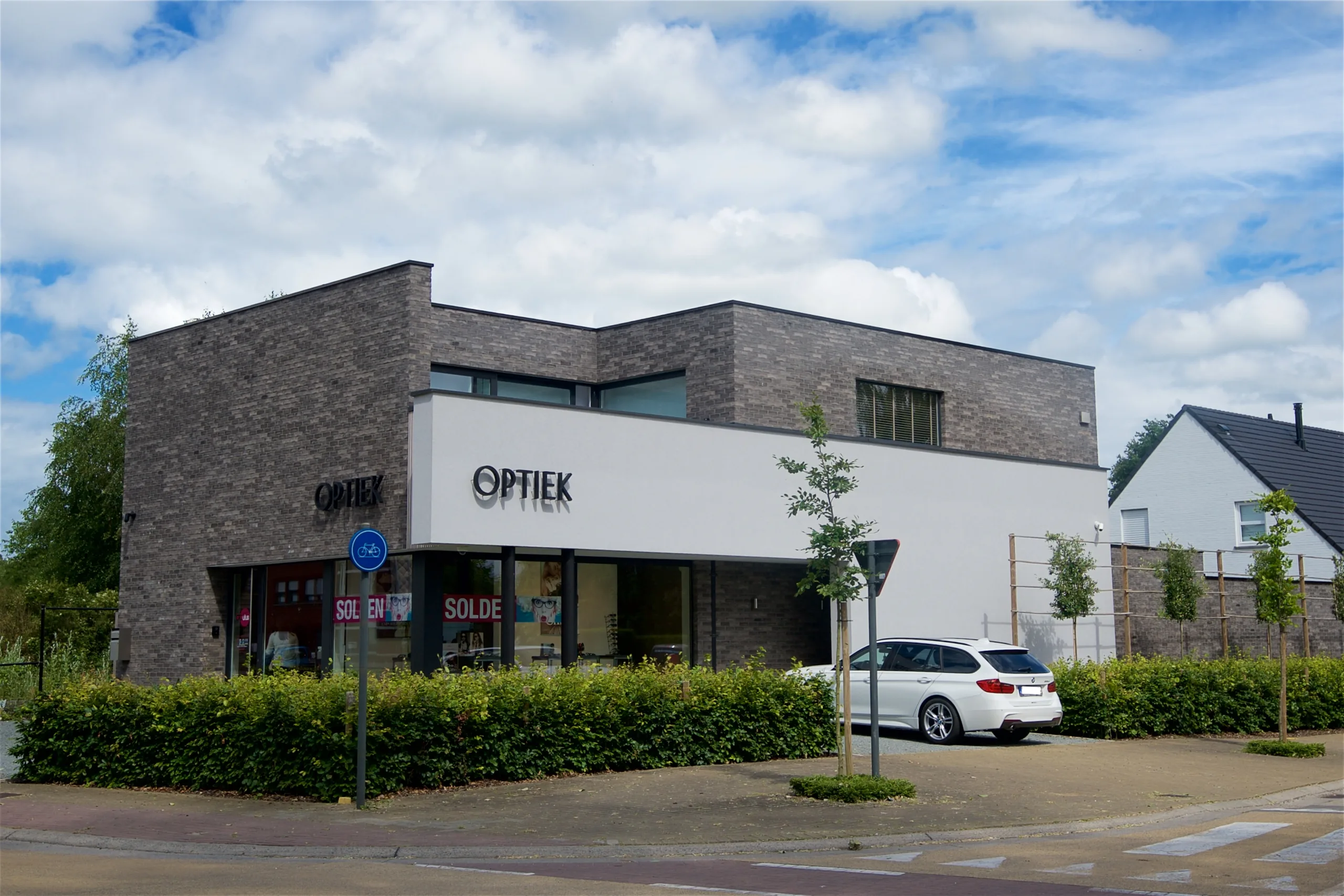 Moderne winkelgevel met baksteenwerk en witte elementen in een verkaveling