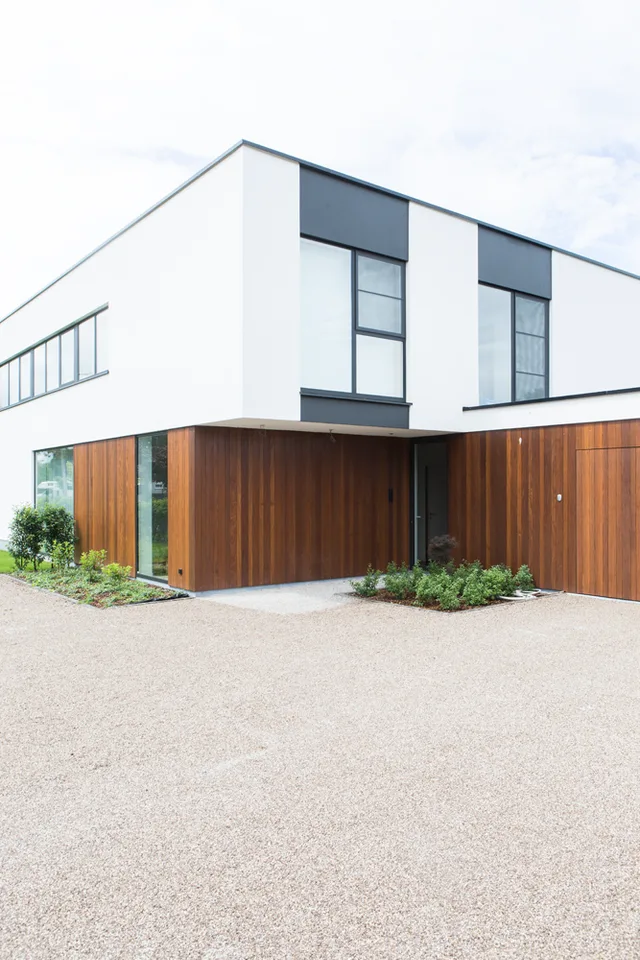 Moderne woning met witte bovenverdieping en houten begane grond, grote raampartijen en inpandige garage
