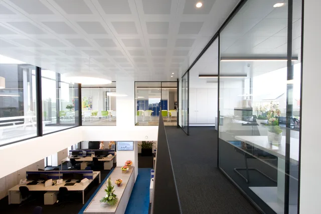 Modern kantoorinterieur met grote glazen scheidingswanden, werkplekken en raampartijen met daglicht