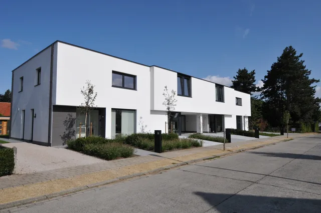 Moderne woning met witte gevelafwerking en grote raampartijen aan de straatzijde