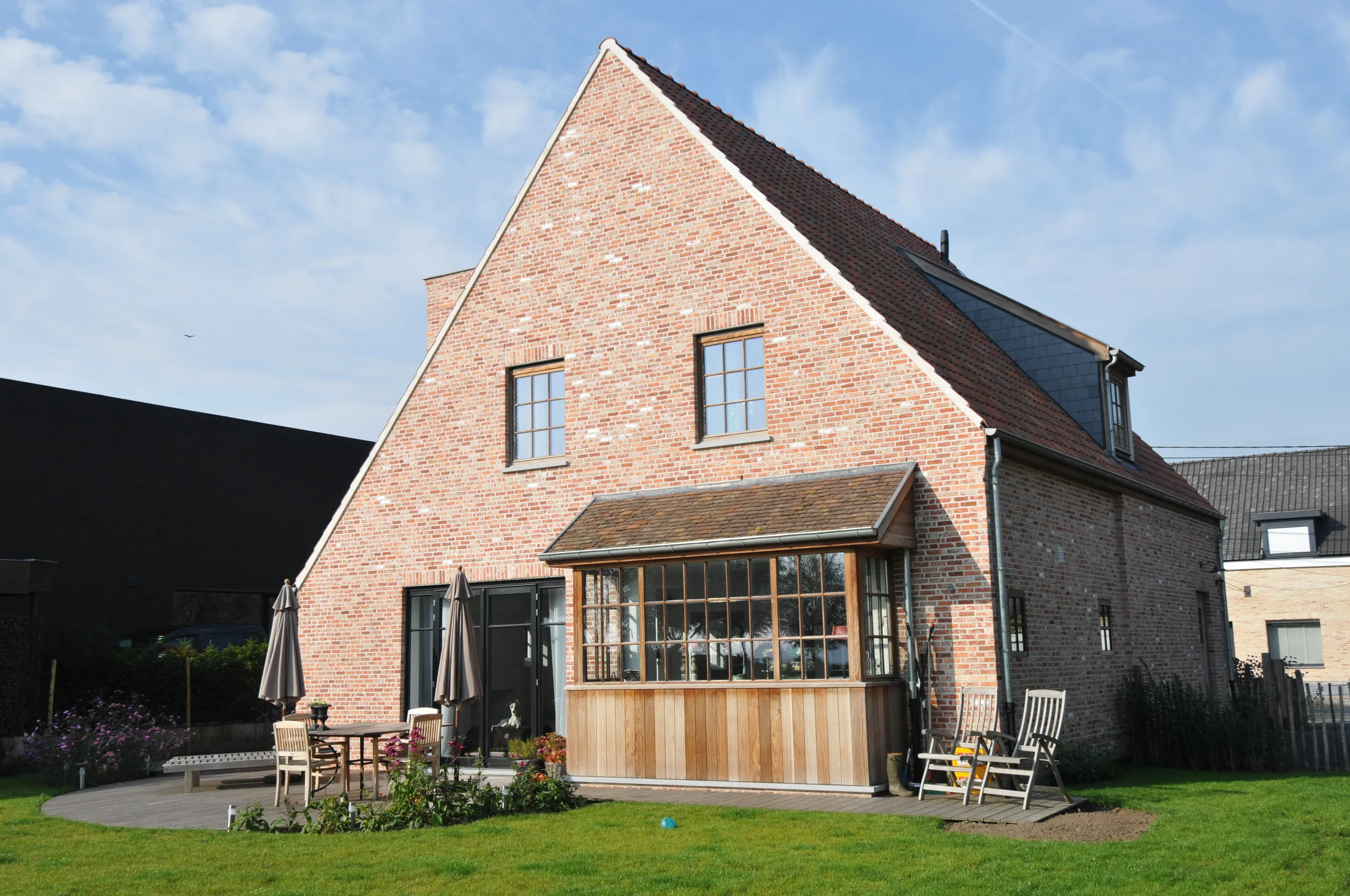 Bakstenen woning met schilddak en moderne houten terrasoverkapping aan de tuinzijde