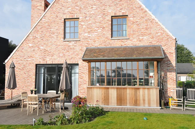 Bakstenen woning met grote raampartijen en houten terrasoverkapping aan de tuinzijde