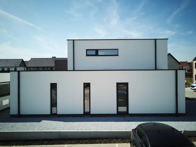 Moderne woning met witte gevel, drie donkere deuren en horizontaal raam op bovenverdieping