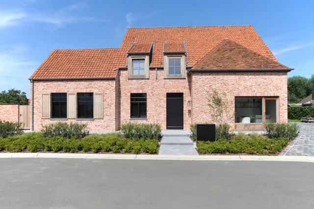 Voorgevel van een nieuwbouwwoning in baksteen met dakkapellen en zwarte raamlijsten