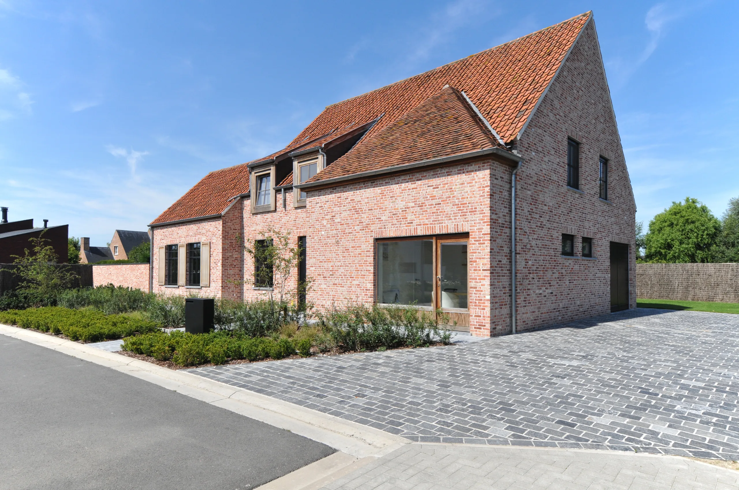 Moderne bakstenen woning met zadeldak, dakkapel en grote glaspartijen aan de voorgevel