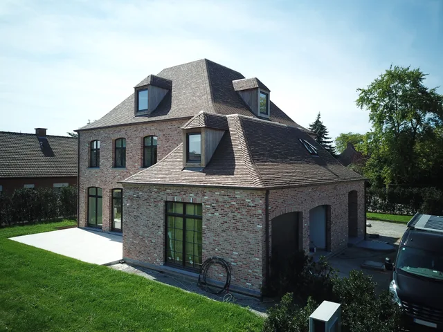 Voorgevel van een traditionele bakstenen woning met mansardedak en dakkapels