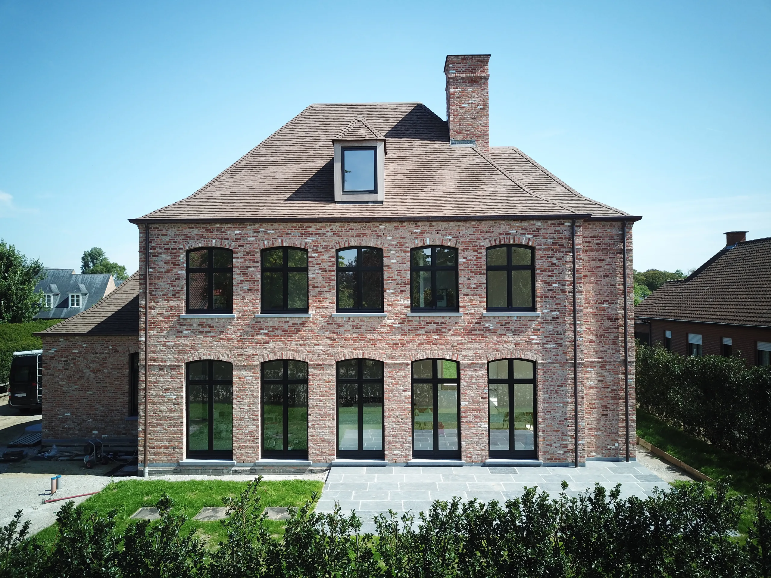 Voorgevel van een nieuwbouw in rode baksteen met grote raampartijen en dakkapel