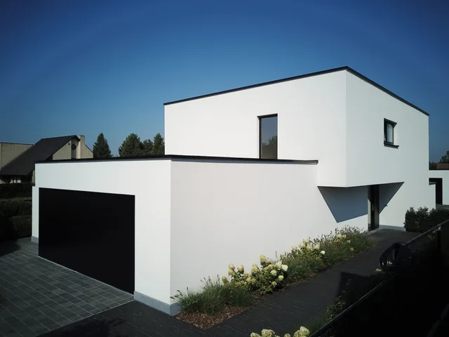 Moderne woning met witte gevel, zwart dak en garage, voorzijde met tuin