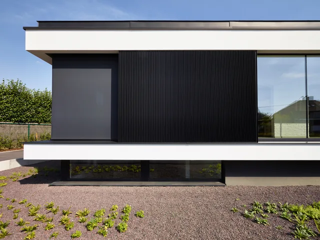 Moderne gevel met wit topgedeelte, zwarte verticaliteit en grote glaspartijen