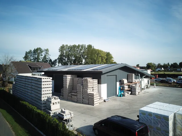 Bouwterrein met gestapelde bouwmaterialen en een werkschuur onder constructie