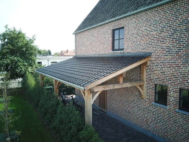 Houten terrasoverkapping met donker dak tegen bakstenen woning