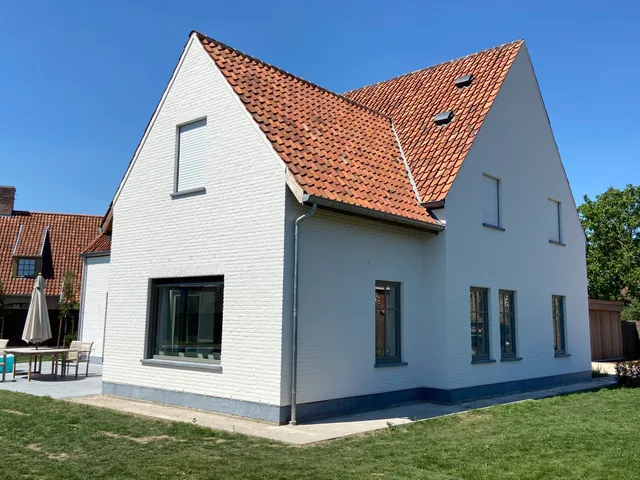 Moderne woning met wit gevelbekleding, oranje dakpannen en grote raampartijen op de tuinzijde