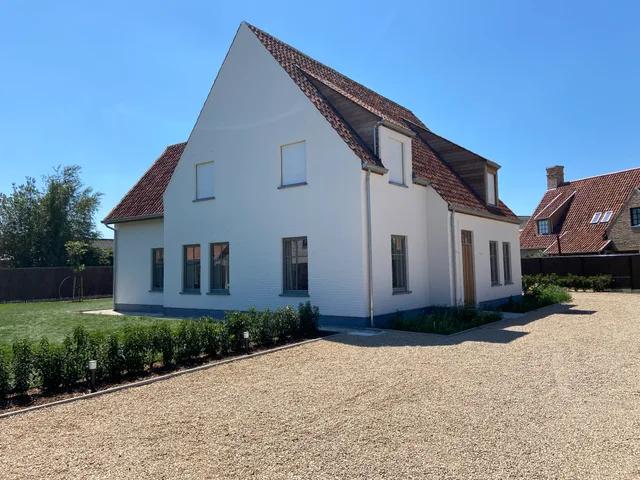 Witte boerderij met oranje dakpannen en blauwe plint, oprit en voortuin
