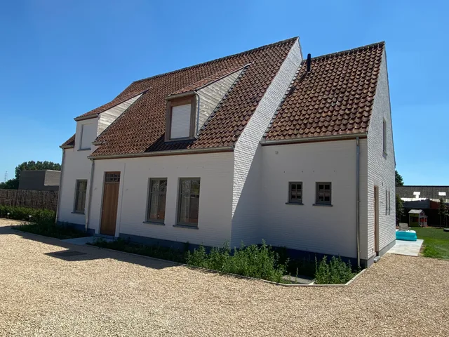 Woning met witte crepi en donkere dakpannen, dakkapel en moderne raamindeling