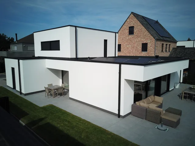 Moderne woning met witte gevel en aangeboude bestaande rode baksteenwoning, zicht op terras en tuin