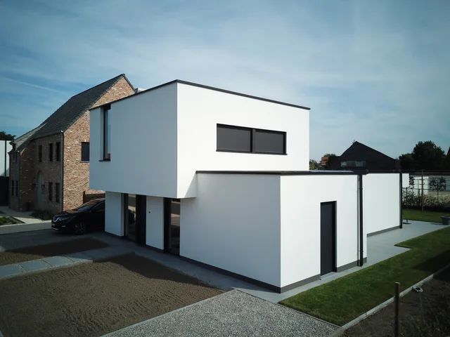 Woning met wit gevelwerk en grote zwarte raampartijen naast bestaande rode gevelsteen