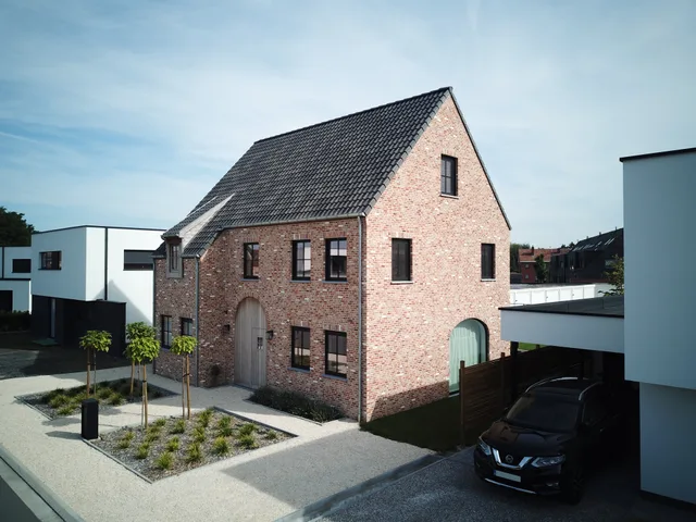 Voorgevel van een gerestaureerde bakstenen woning met modern uitgebreide zijvleugels in witte crepi
