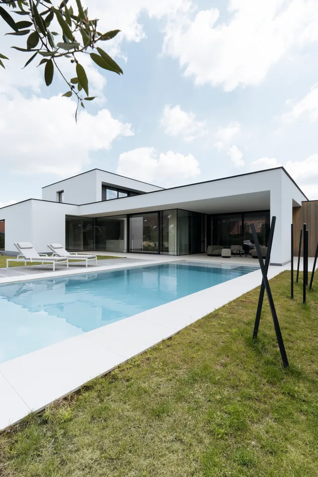 Moderne witte villa met grote glaspartijen en zwembad in de tuin