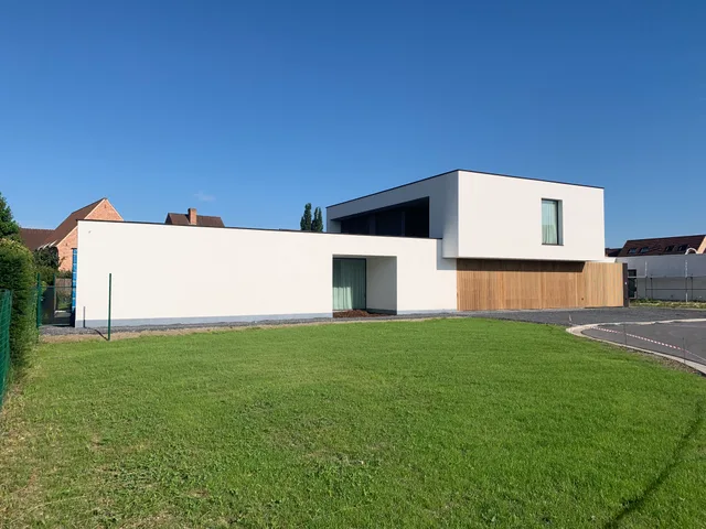 Moderne witte woning met houten accenten en grote glaspartijen, gezien vanaf de voortuin