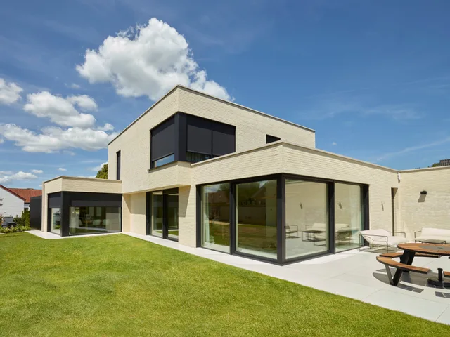 Moderne woning met witte gevelsteen, grote raampartijen en tuinzijde met terras
