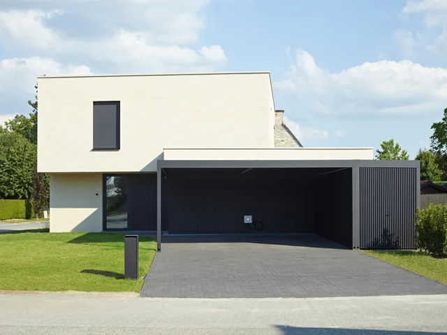 Moderne woning met witte gevel, carport met donkergrijze lamellen en verharde voorzone