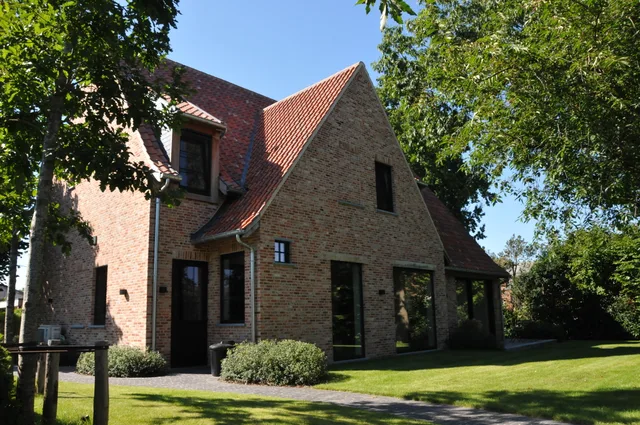 Voorgevel van een moderne woning in baksteen met rode pan en grote raampartijen