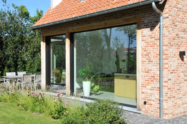 Moderne tuinzijde met grote glazen schuifpui en houten kozijnen, uitkijkend op aangelegde tuin