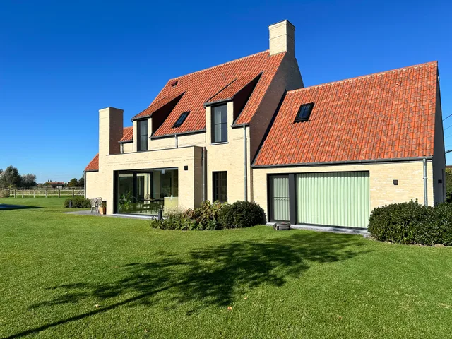 Nieuwbouwwoning met crèmekleurige gevelsteen, rode pannendak en dakkapels aan de straatzijde