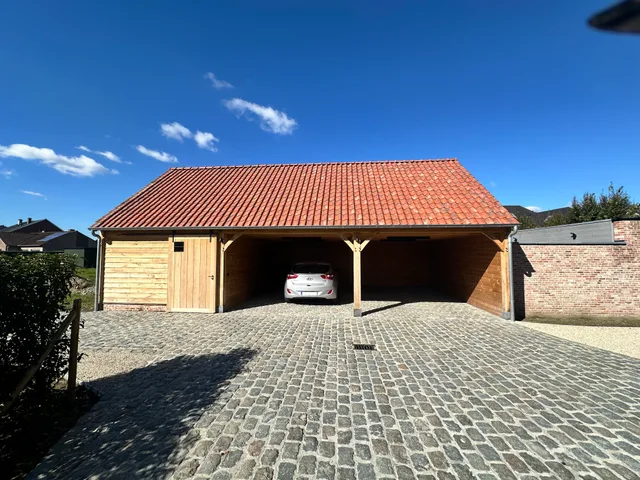 Moderne carport met houten constructie en terracotta dak op geplaveide oprit