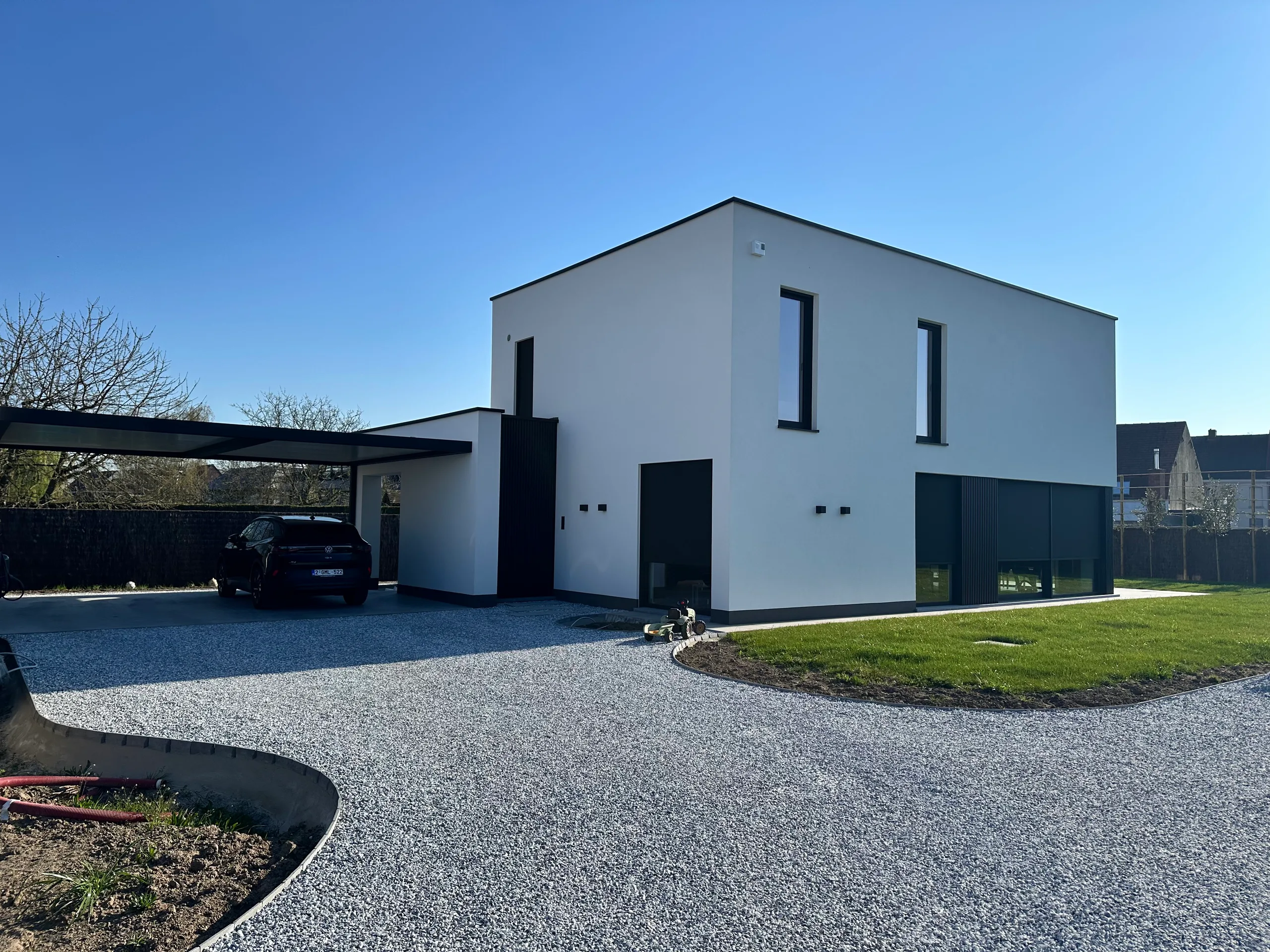 Moderne woning met witte crepi en carport aan de straatfront