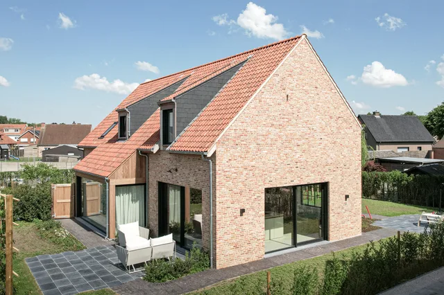 Moderne woning met rode bakstenen gevel, dakkapels en grote raampartijen aan de voorzijde