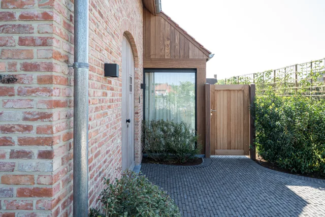Achtertuin met terras, houtenbijgebouw en beplanting tegen bakstenen woning