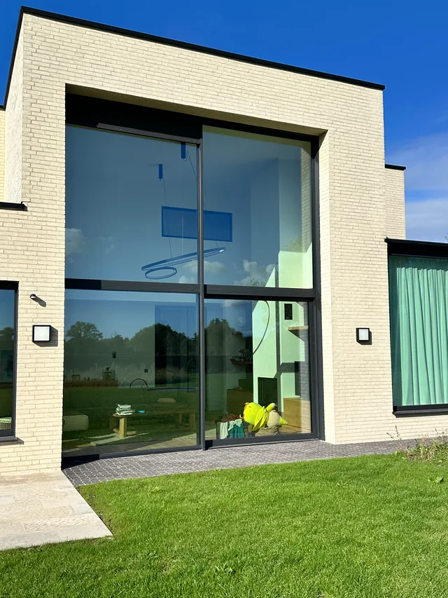 Achtergevel van woning met grote glazen schuifdeuren en witte bakstenen gevelbekleding