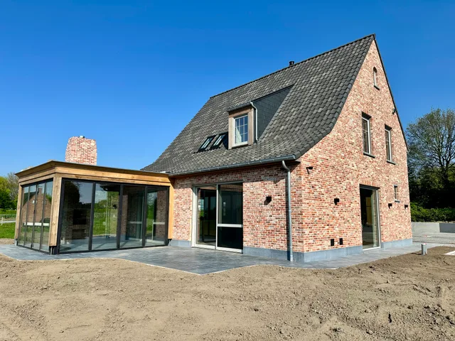 Nieuwbouwwoning met bakstenen gevel, zadeldak en moderne overkapping aan de tuinzijde