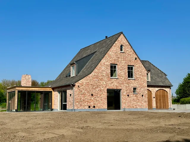 Nieuwbouwwoning in rood baksteen met moderne glazen uitbouw aan de zijkant