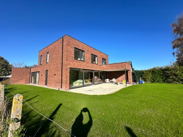 Moderne bakstenen woning met grote raampartijen en overdekte terras aan de tuinzijde