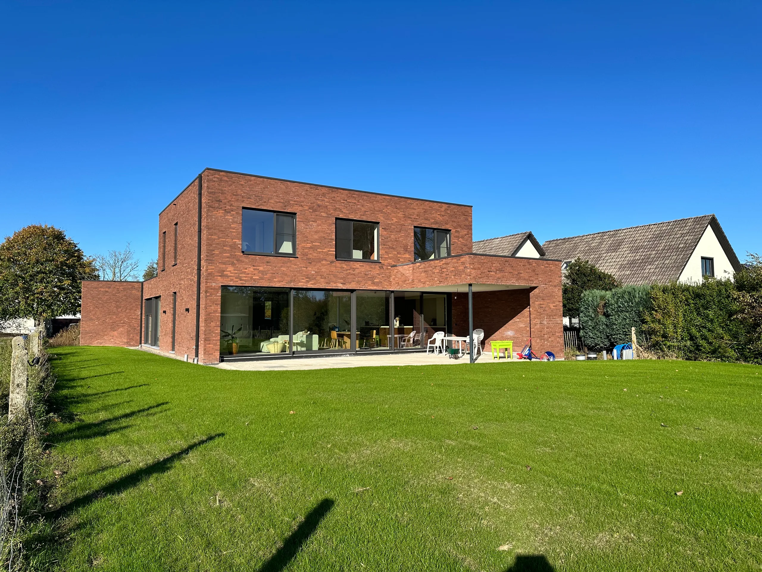 Moderne bakstenen woning met uitgebreide glazen gevel en open tuin