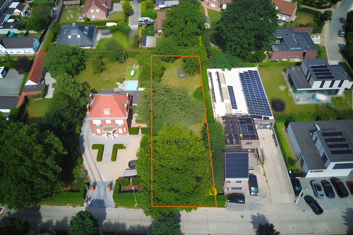 Luchtfoto van een bouwkavel in een residentiële buurt met aangrenzende bebouwing