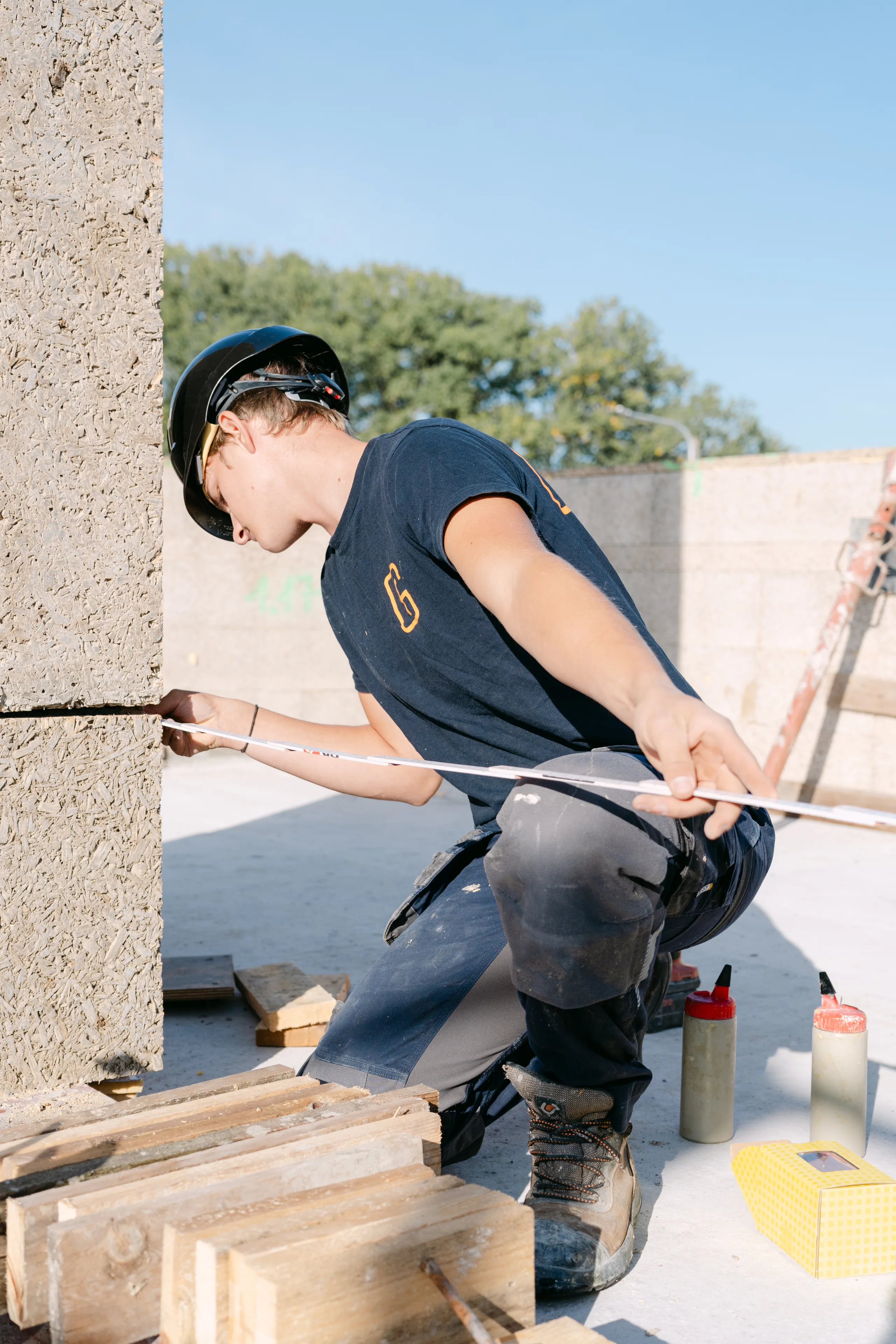 Werker voegt betonnen gevelplaten af met kit op een bouwwerf
