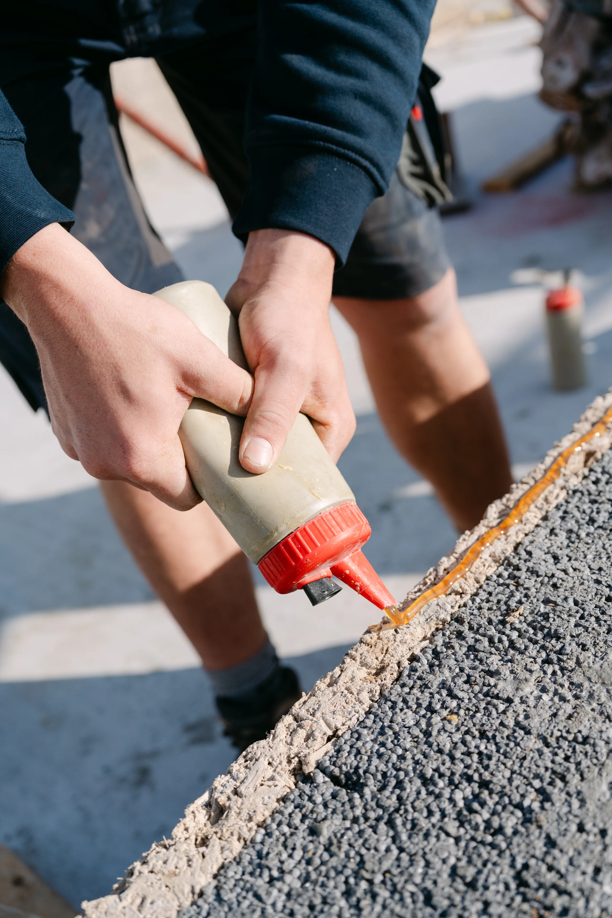 Handen brengen lijm aan op betonwerk tijdens bouwwerkzaamheden op de werf