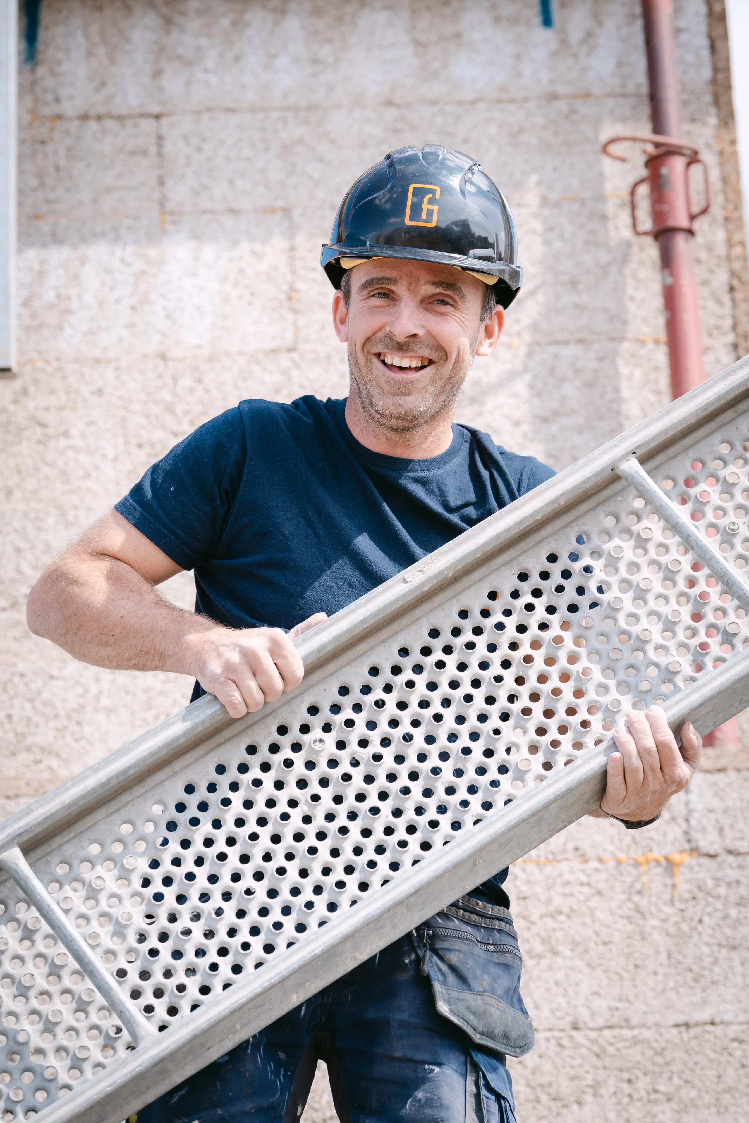 Bouwvakker met helm houdt een metalen loopplank vast op een werf