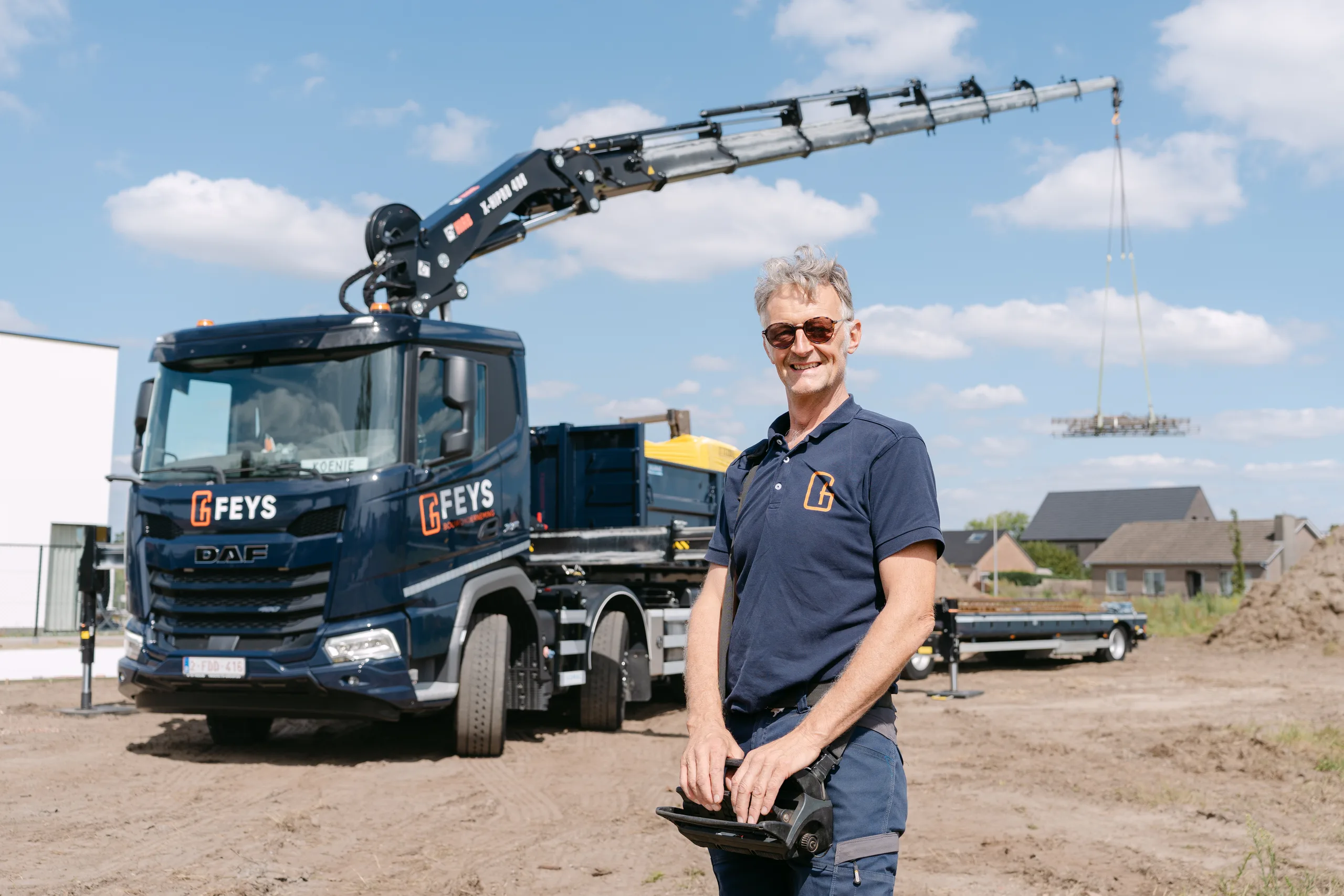 Man met bedrijfskleding op een bouwwerf naast een vrachtwagen met hijskraan