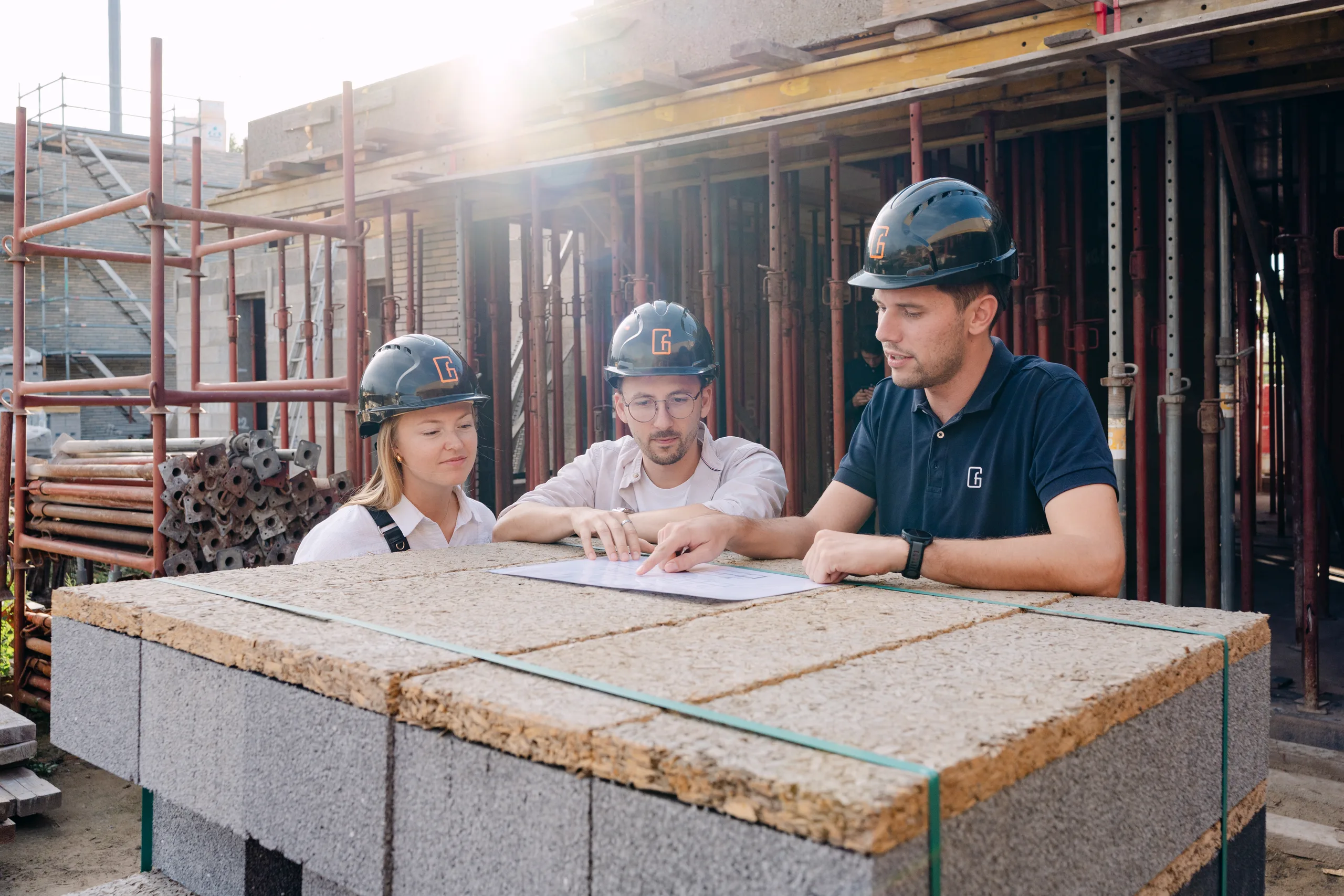 Drie bouwvakkers overleggen over bouwplannen op een werktafel op de bouwplaats