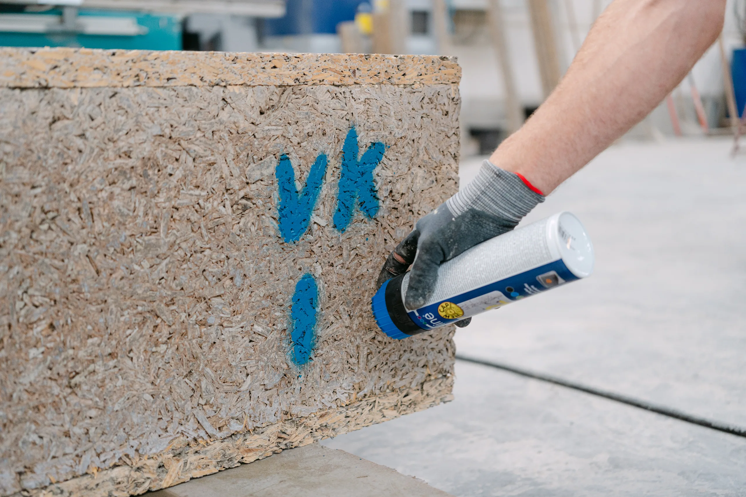 Hand met verfspuit markeert bouwmateriaal op een werf