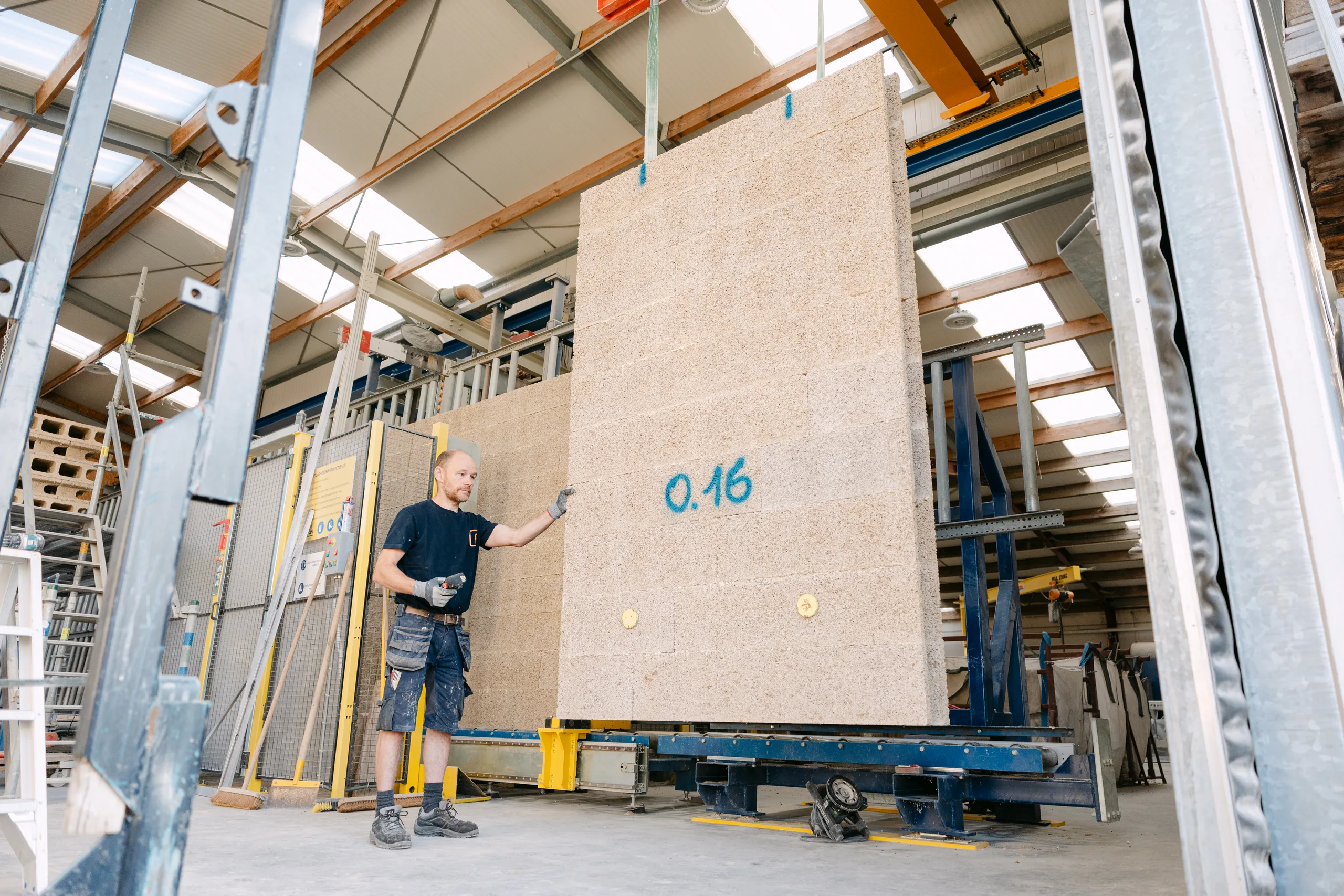Man op een bouwwerf bij een grote betonnen gevelplaat met meting erop