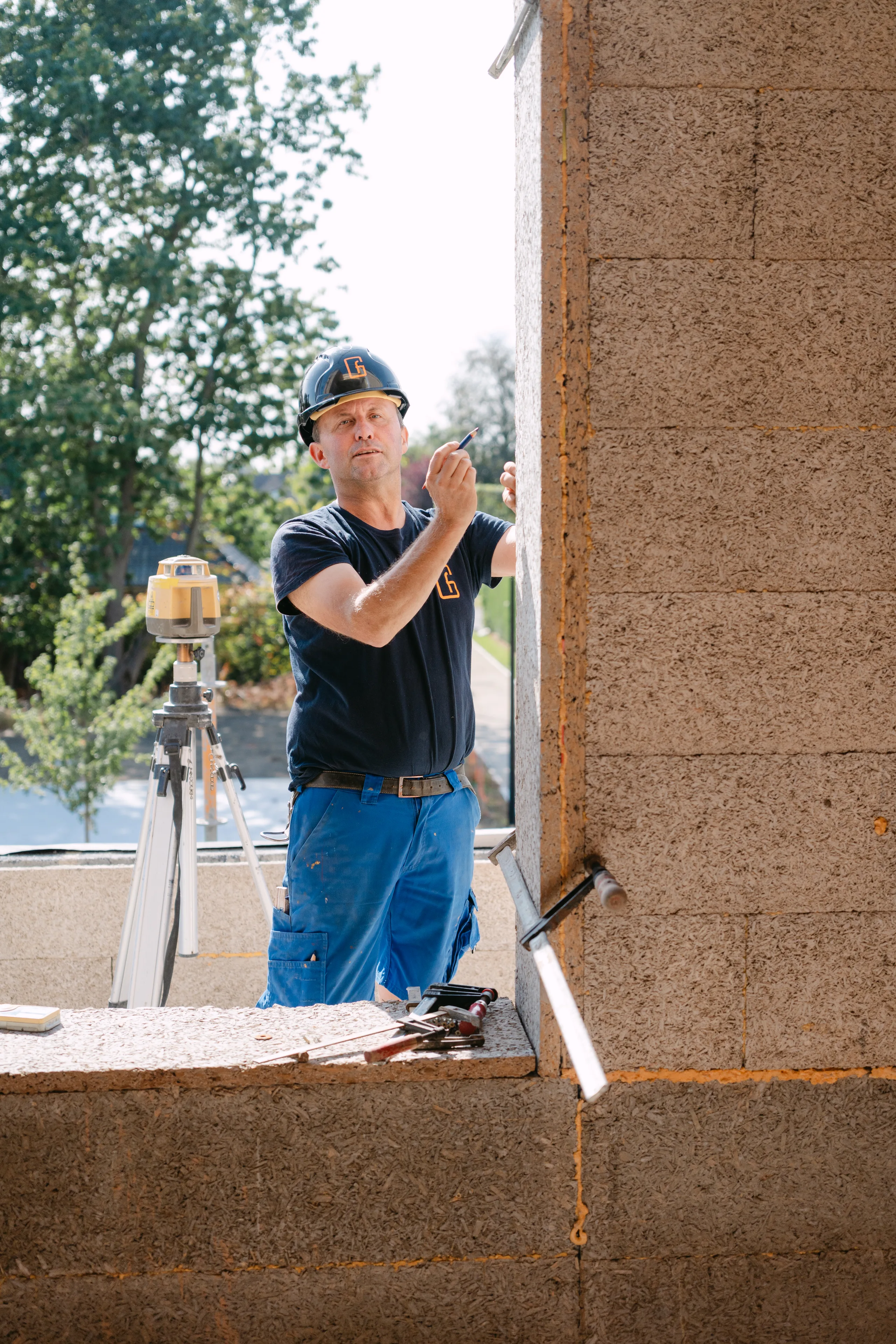 Bouwvakker meet op een betonnen constructie met lasermeetapparaat op een bouwwerf
