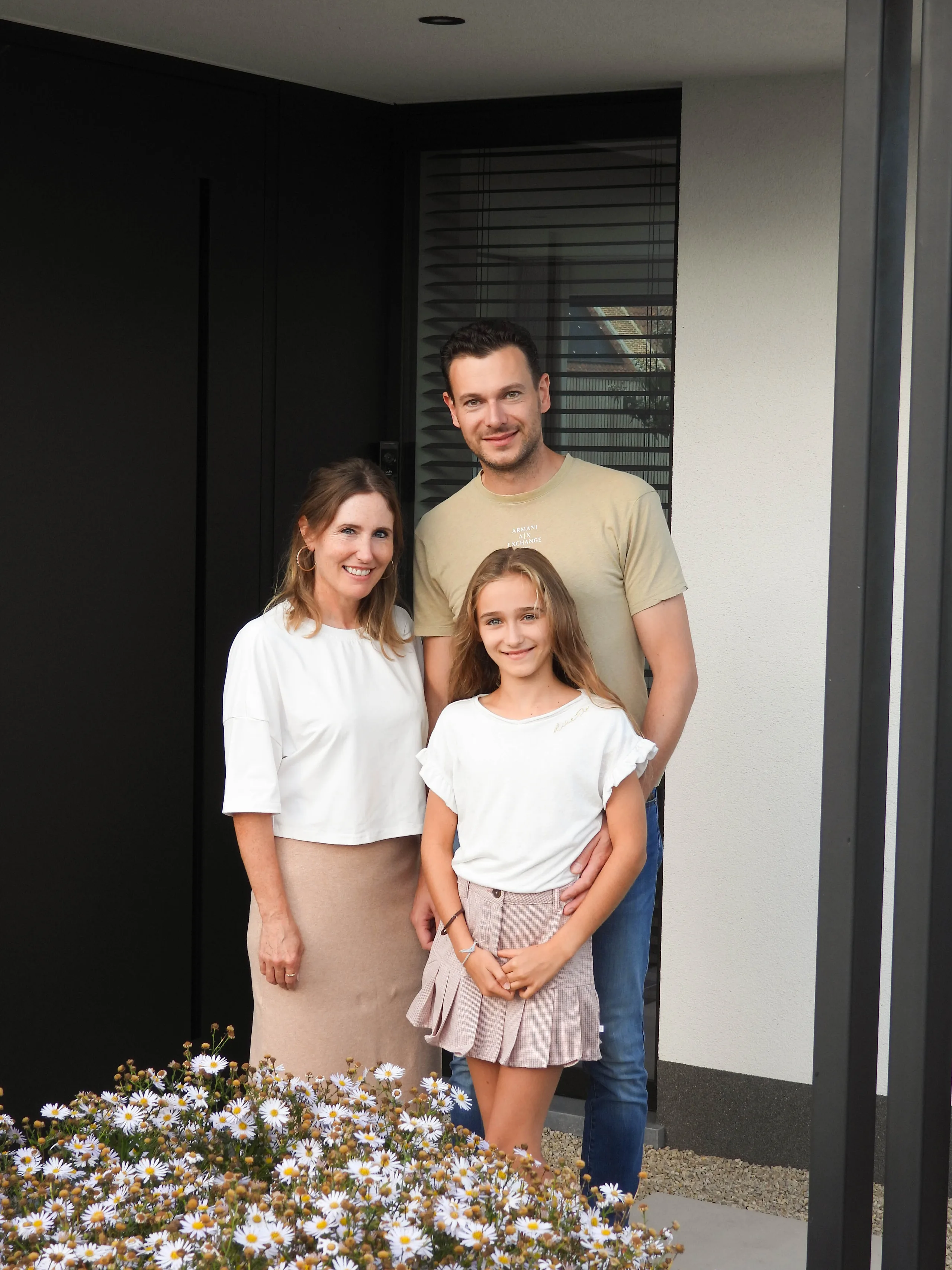 Familie in de inkom van een woning met moderne witte wanden en donkere deur